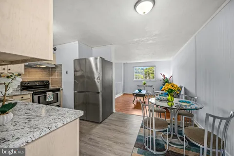 a kitchen with stainless steel appliances granite countertop a table chairs and a refrigerator