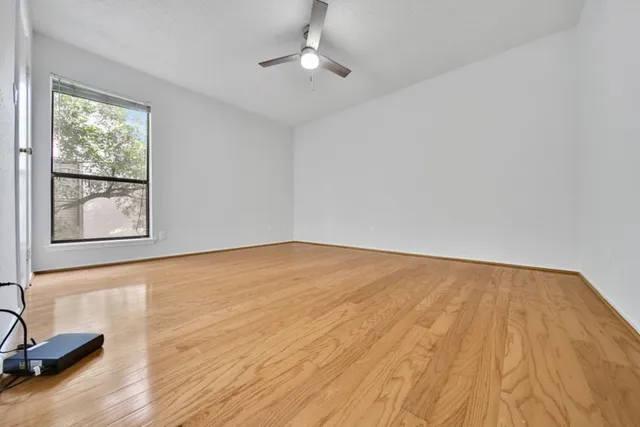 a view of an empty room with a window and wooden floor