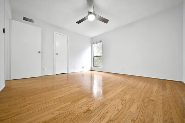 a view of empty room with wooden floor and fan