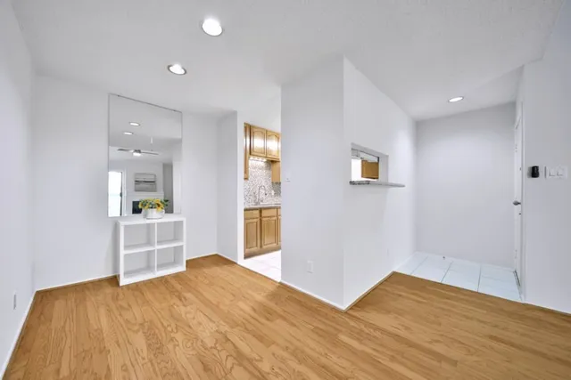 a view of kitchen and empty room with wooden floor