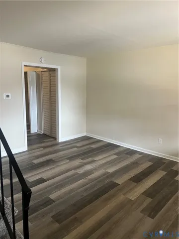a view of empty room with wooden floor and stairs