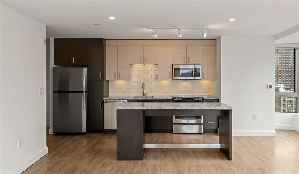 99 Kneeland Street, Unit 1301 Boston, MA 02111 - Photo 4 of 14 a kitchen with stainless steel appliances granite countertop a stove and a refrigerator