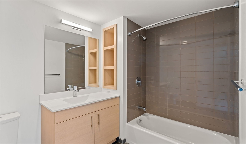 99 Kneeland Street, Unit 1301 Boston, MA 02111 - Photo 7 of 14 a bathroom with a shower sink vanity and mirror