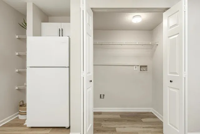a view of a kitchen with refrigerator and wooden floor
