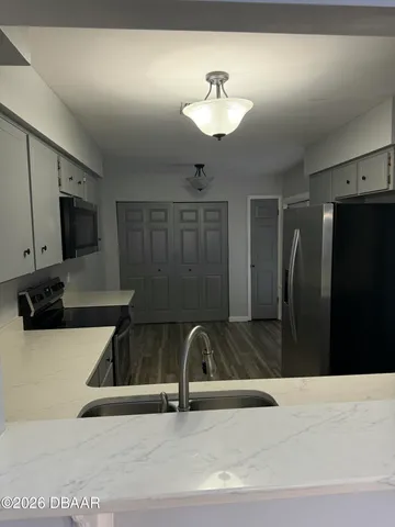 a view of a kitchen with a sink and refrigerator