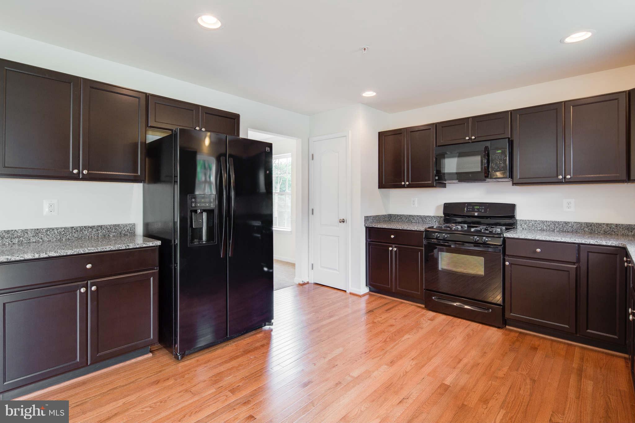 4 Hanover Road Hanover, MD 21076 - Photo 8 of 30 a kitchen with granite countertop a refrigerator and a stove top oven