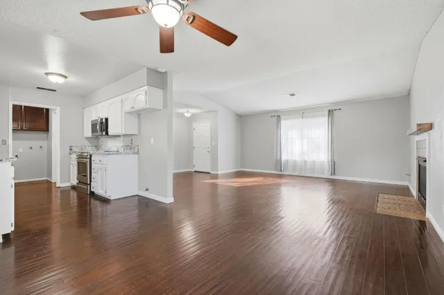 a view of a kitchen with a fridge wooden floor and a window