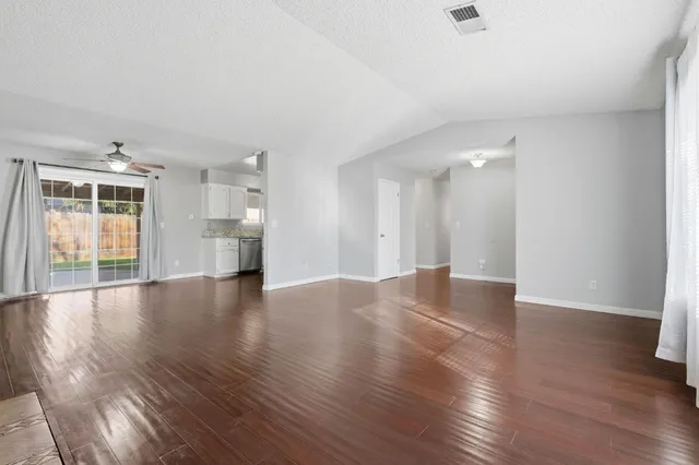 a view of empty room with wooden floor and windows