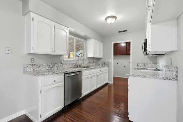 a kitchen with granite countertop cabinets stainless steel appliances a sink and a window