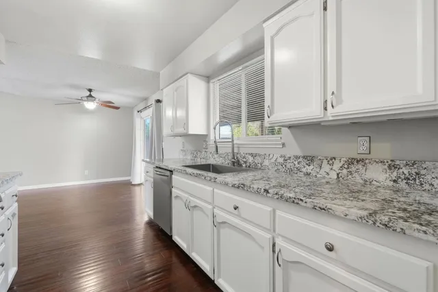 a kitchen with granite countertop white cabinets and a sink