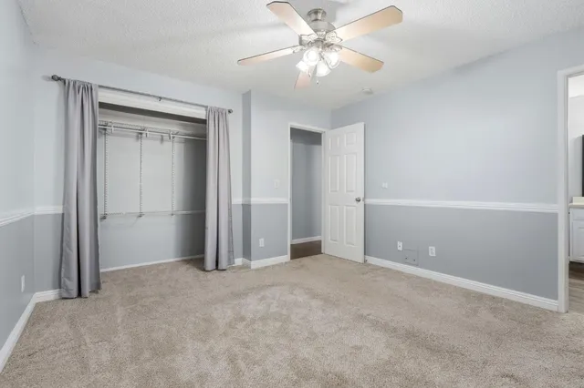 an empty room with closet and a chandelier fan