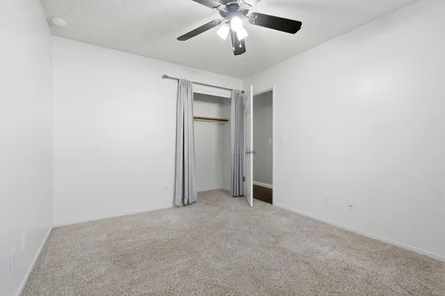 an empty room with a ceiling fan and a window