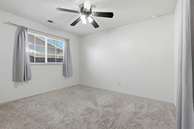 an empty room with windows and fan