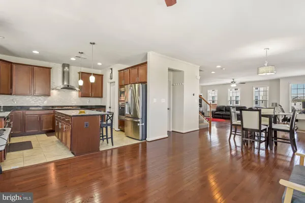a kitchen with stainless steel appliances kitchen island granite countertop a table chairs and a refrigerator