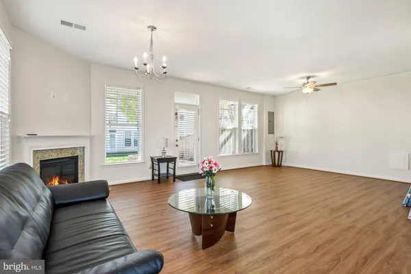 a living room with couches a fireplace and a chandelier