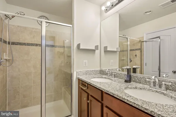 a bathroom with a granite countertop shower sink vanity and mirror