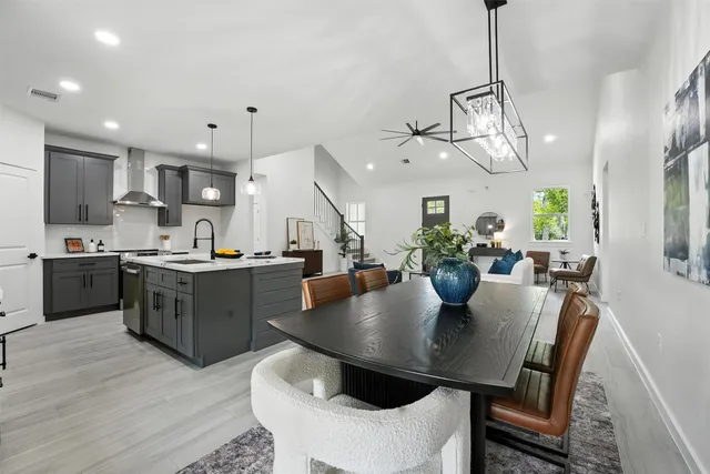 a kitchen with kitchen island a dining table chairs stainless steel appliances and cabinets