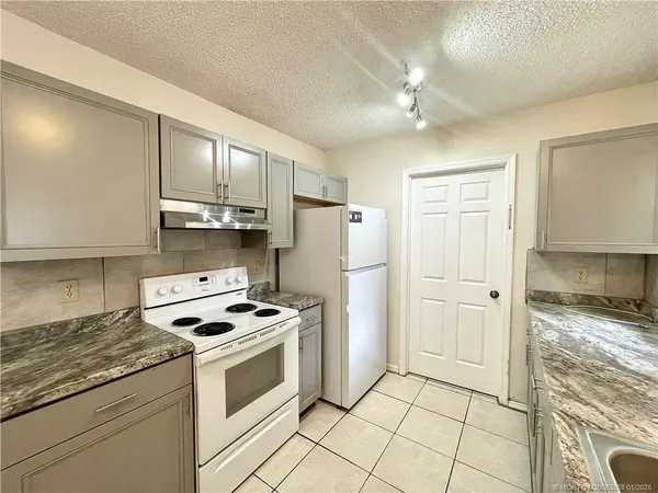 a kitchen with granite countertop a sink stove and refrigerator