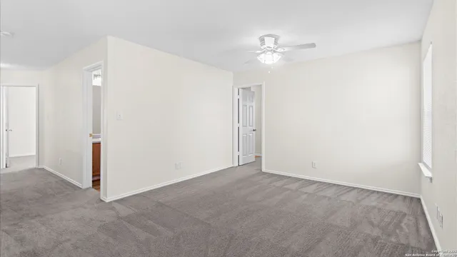a view of an empty room with a chandelier fan
