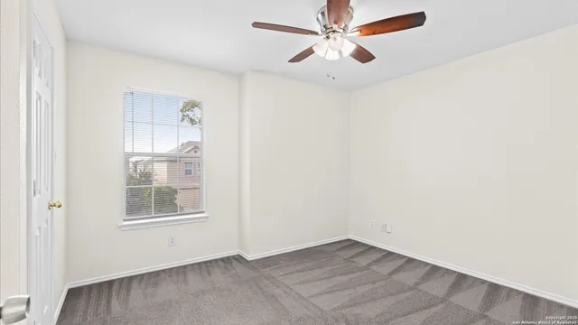 an empty room with windows and fan
