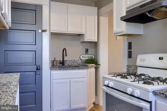 a kitchen with granite countertop a stove and a white cabinets