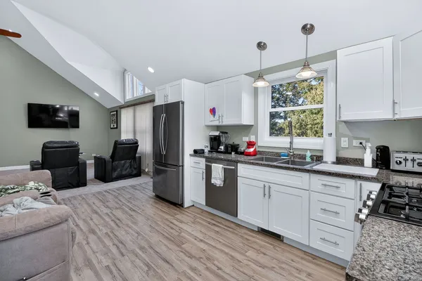 a kitchen with granite countertop a sink cabinets stainless steel appliances and a window
