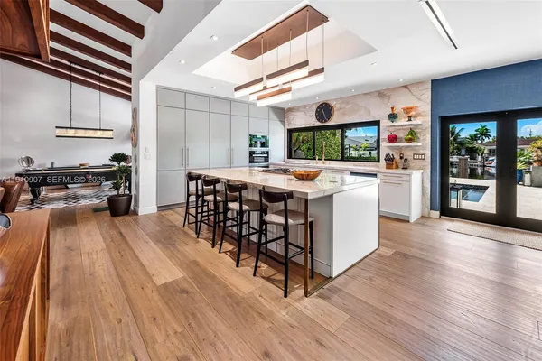 a kitchen with stainless steel appliances a stove top oven a sink dishwasher and a refrigerator with wooden floor