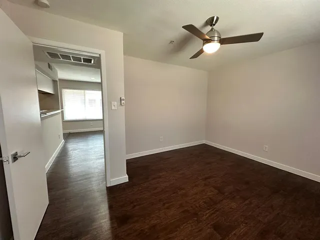 a view of empty room with wooden floor and fan