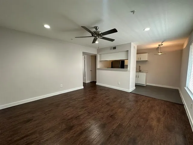an empty room with wooden floor and a ceiling fan