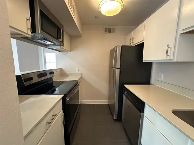 a kitchen with stainless steel appliances a refrigerator a sink and white cabinets