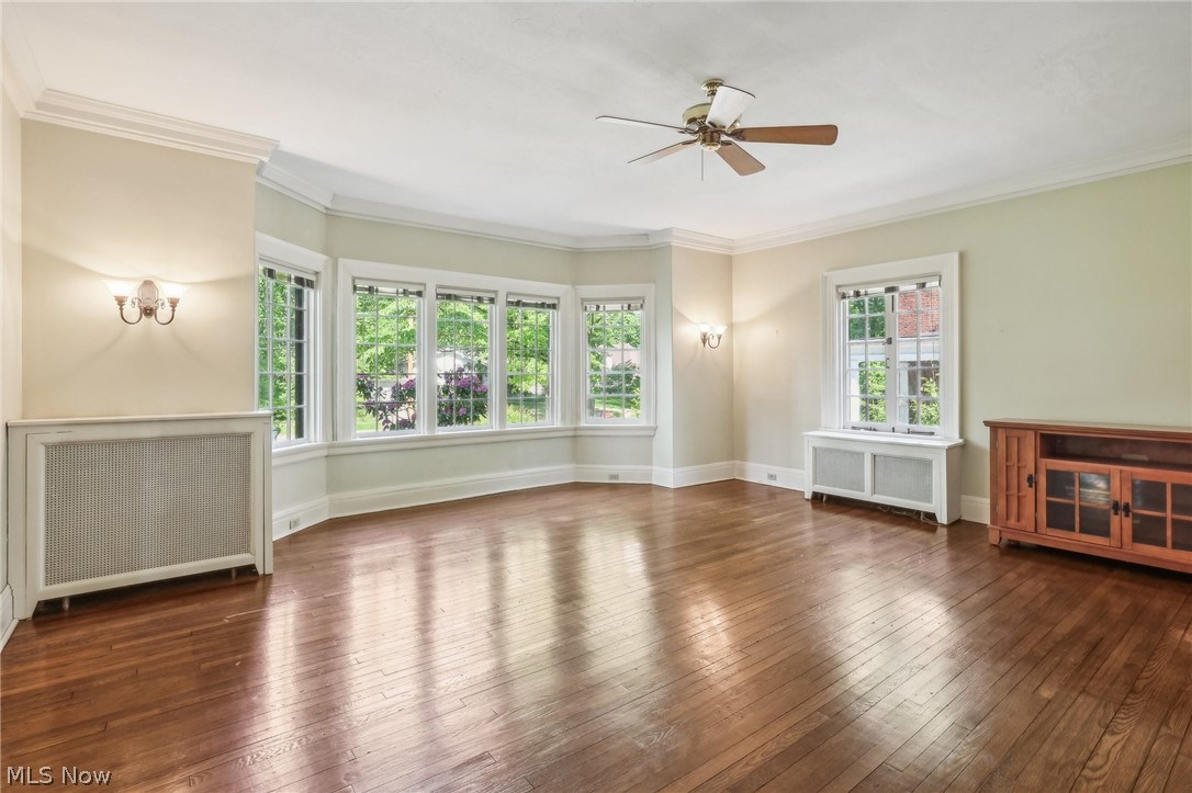 2329 Stillman Road Cleveland, OH 44118 - Photo 5 of 49 Unfurnished living room with a healthy amount of sunlight, crown molding, dark hardwood / wood-style floors, and radiator