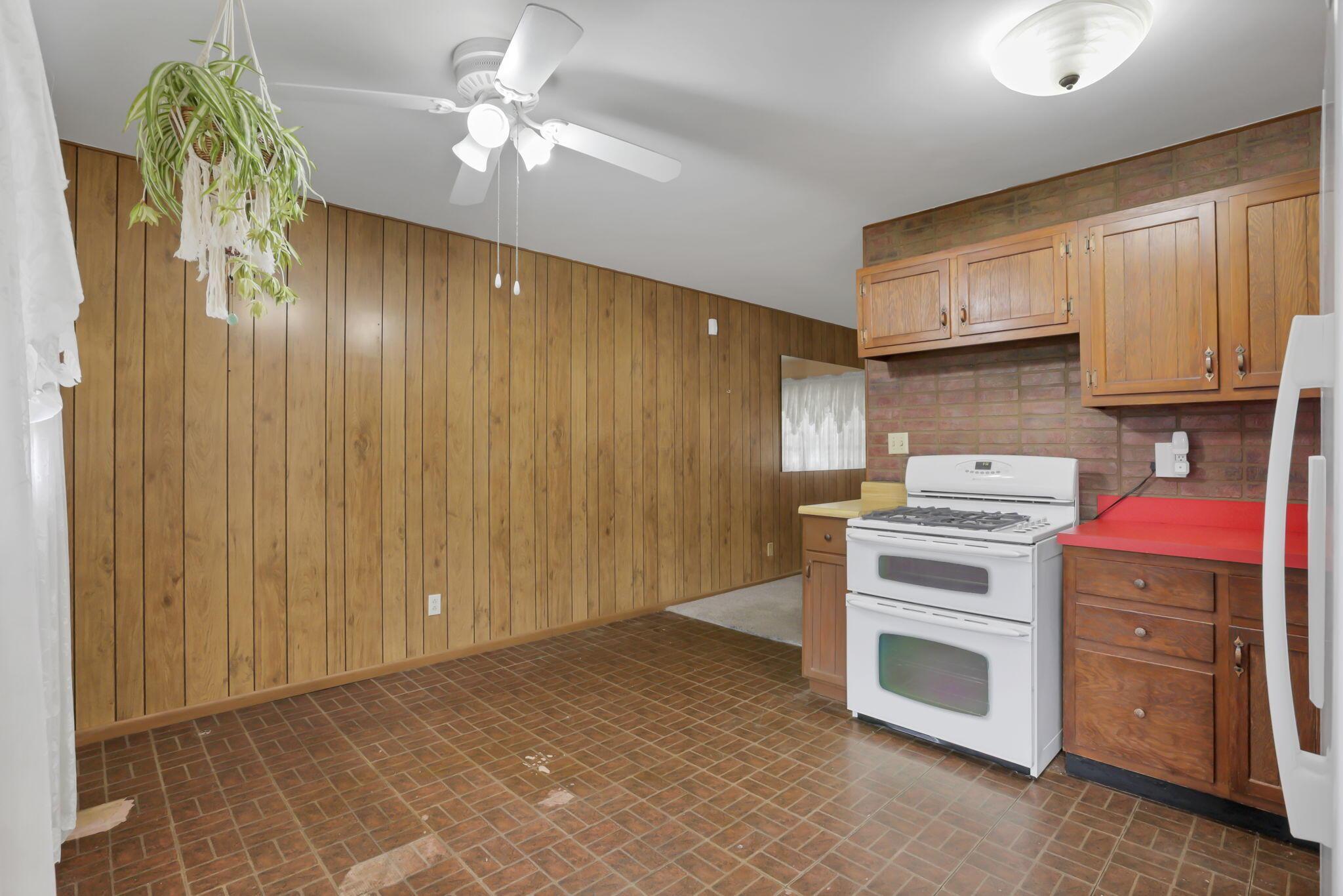 3882 Glenfield Road Columbus, OH 43232 - Photo 12 of 29 Kitchen space featuring wood paneling, brick-patterned backsplash, and a white double oven range