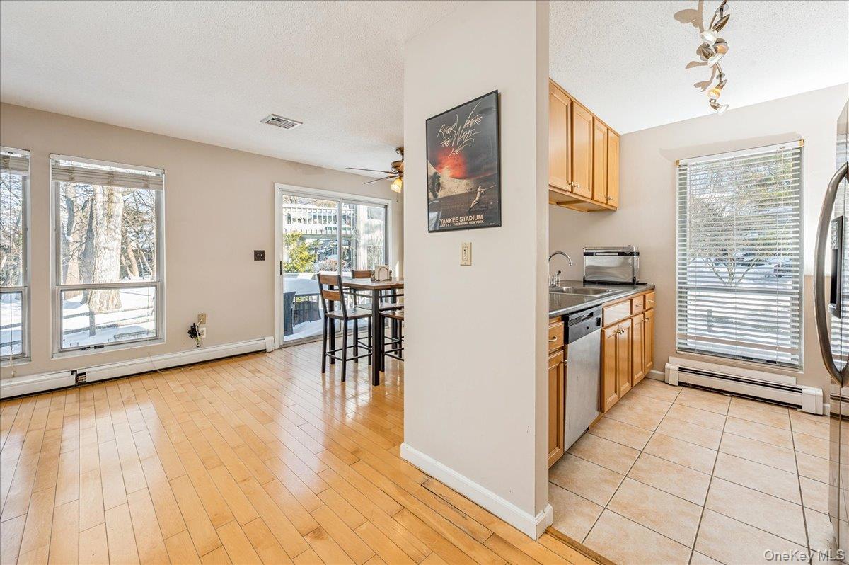 58 Villa Drive Peekskill, NY 10566 - Photo 2 of 21 Kitchen featuring a baseboard heating unit, a textured ceiling, a ceiling fan, stainless steel appliances, and light wood-type flooring