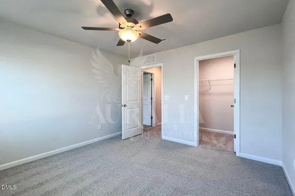 an empty room with chandelier fan and windows