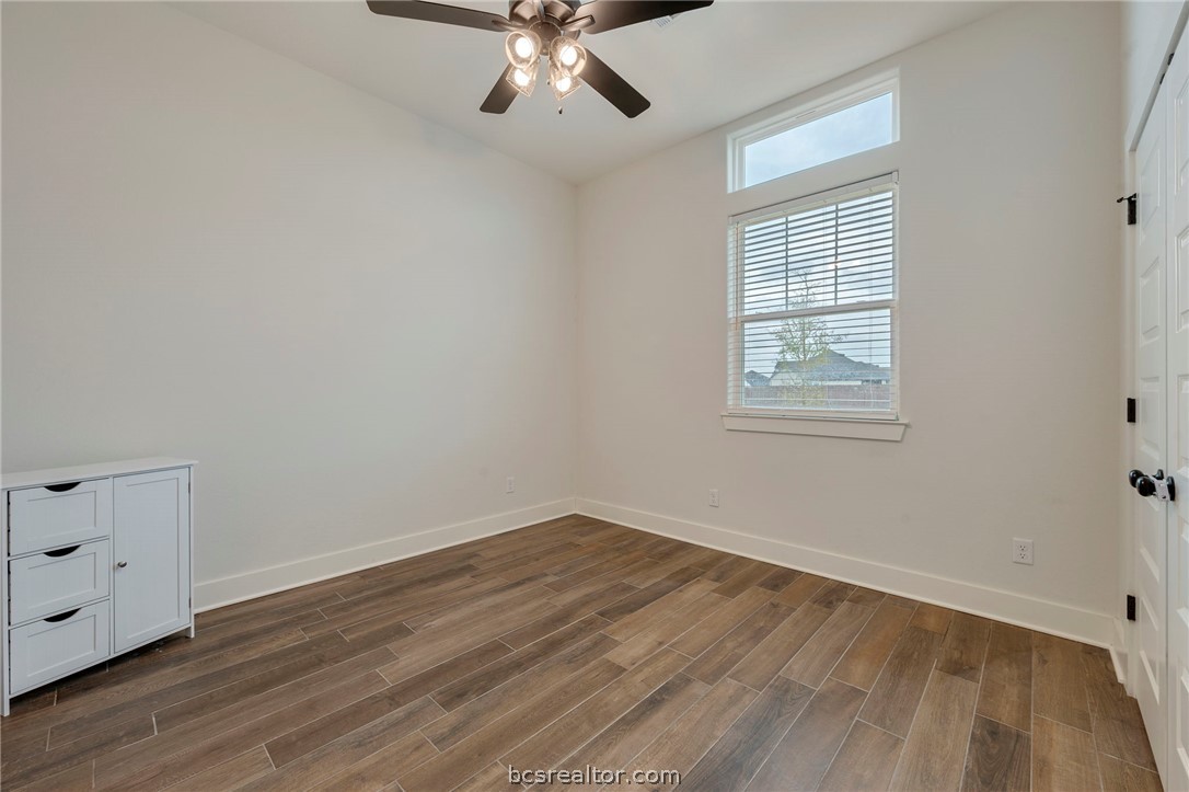 4357 Fox River Lane Bryan, TX 77802 - Photo 14 of 24 an empty room with wooden floor chandelier fan and windows