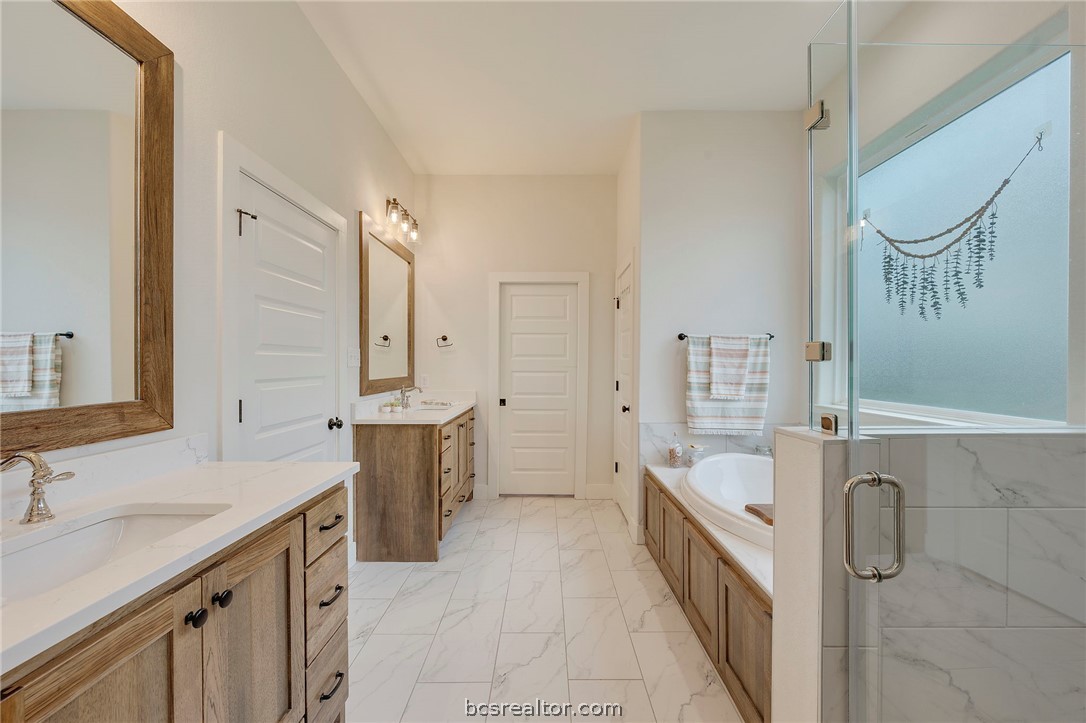 4357 Fox River Lane Bryan, TX 77802 - Photo 17 of 24 a spacious bathroom with a double vanity sink a mirror a bathtub and shower