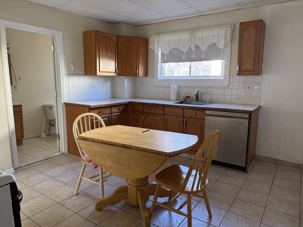 66 Cottage Street, Unit 1 Everett, MA 02149 - Photo 2 of 9 a kitchen with a table chairs sink and cabinets
