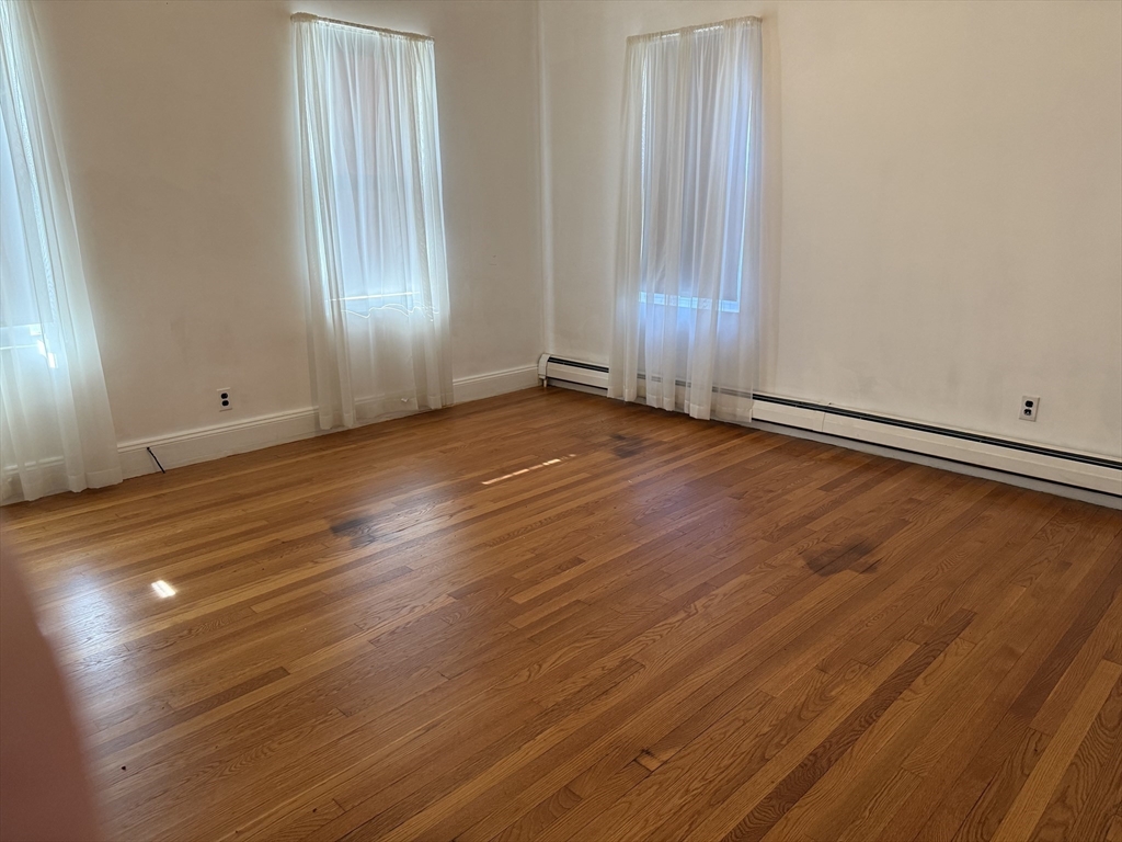 66 Cottage Street, Unit 1 Everett, MA 02149 - Photo 7 of 9 an empty room with wooden floor and windows