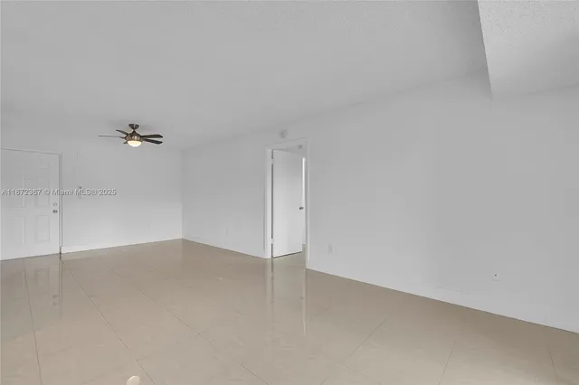 an empty room with a ceiling fan and window