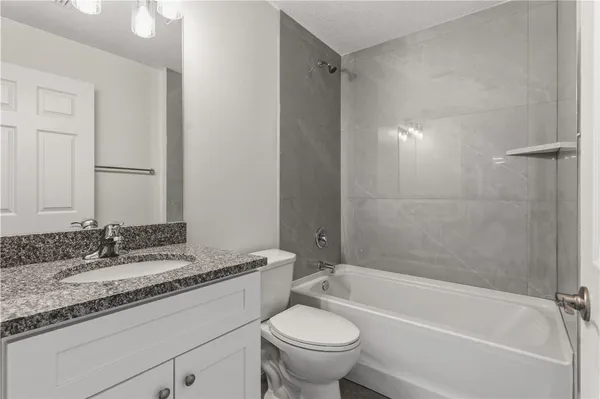 a bathroom with a granite countertop sink a toilet and bathtub