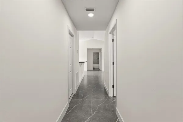 a view of a hallway with wooden floor and a bathroom