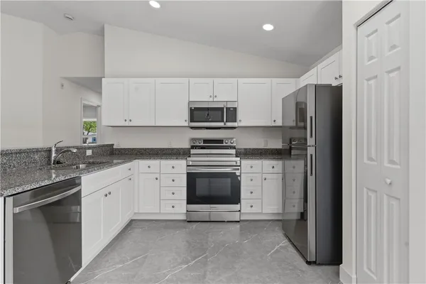 a kitchen with granite countertop white cabinets and stainless steel appliances
