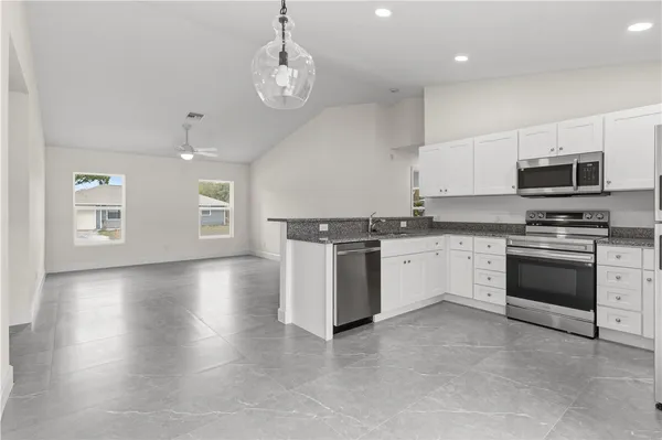 a kitchen with granite countertop a stove cabinets and a refrigerator
