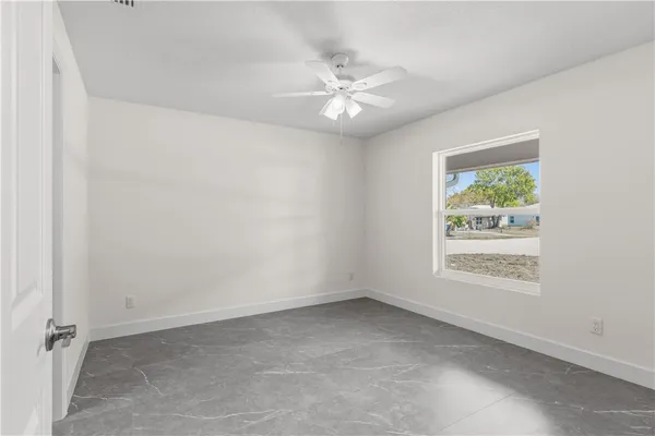 an empty room with windows and fan