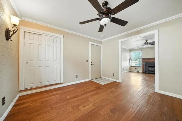 an empty room with wooden floor ceiling fan and window