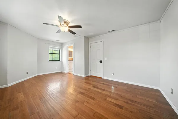 an empty room with wooden floor chandelier fan and windows