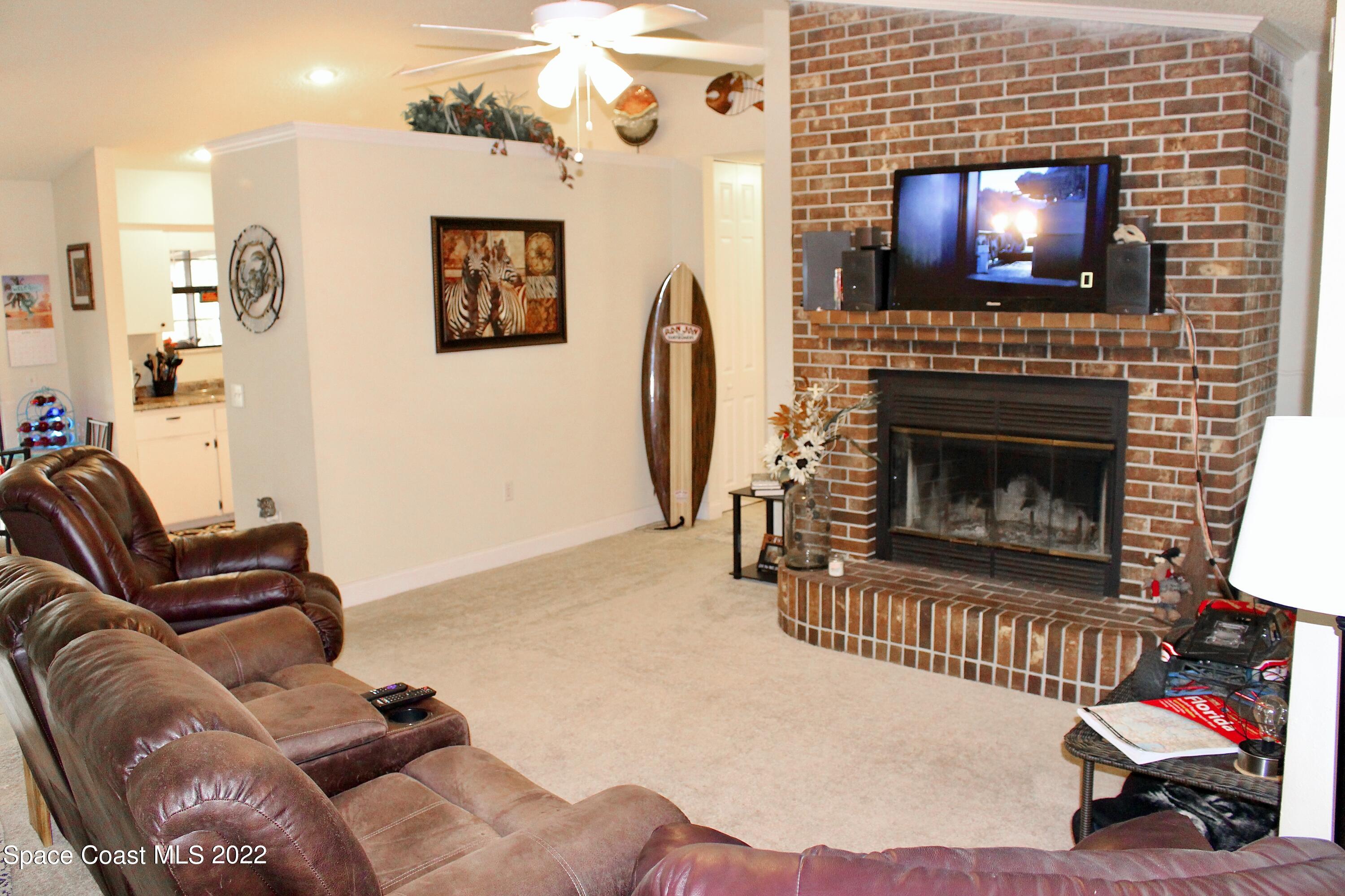 6737 Cecil Road Cocoa, FL 32927 - Photo 12 of 39 a living room with furniture a flat screen tv and a fireplace