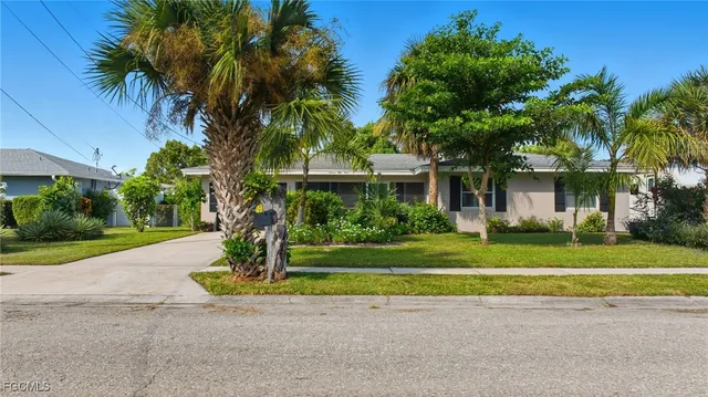 a front view of a house with a garden and trees