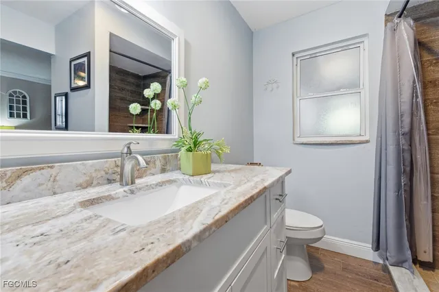 a bathroom with a granite countertop sink a toilet and mirror