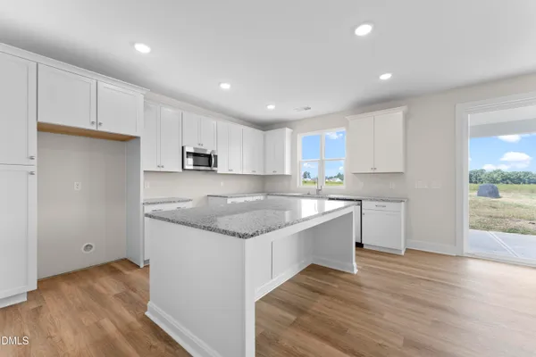 a kitchen with granite countertop white cabinets and wooden floor